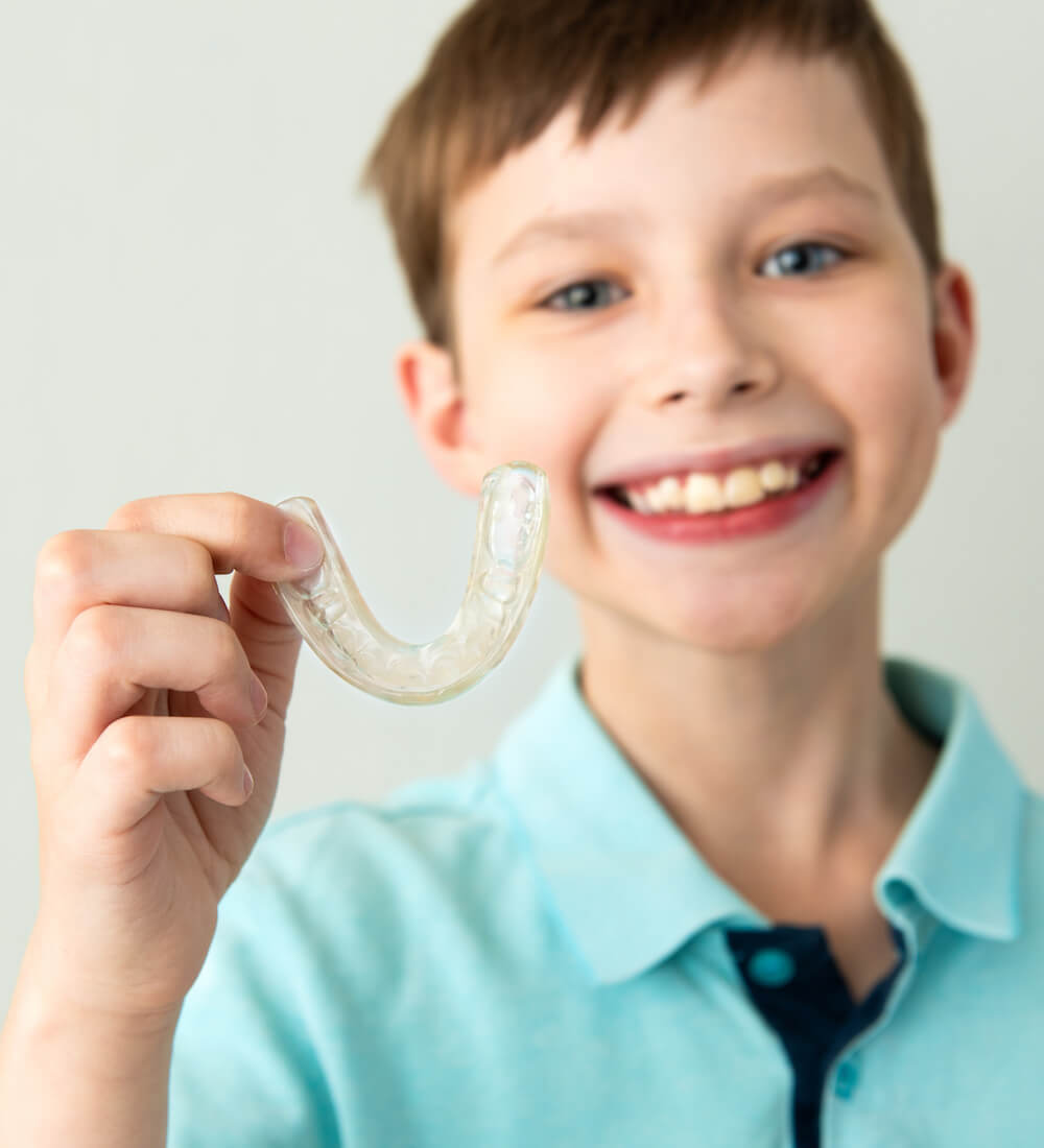 young boy holding aligners